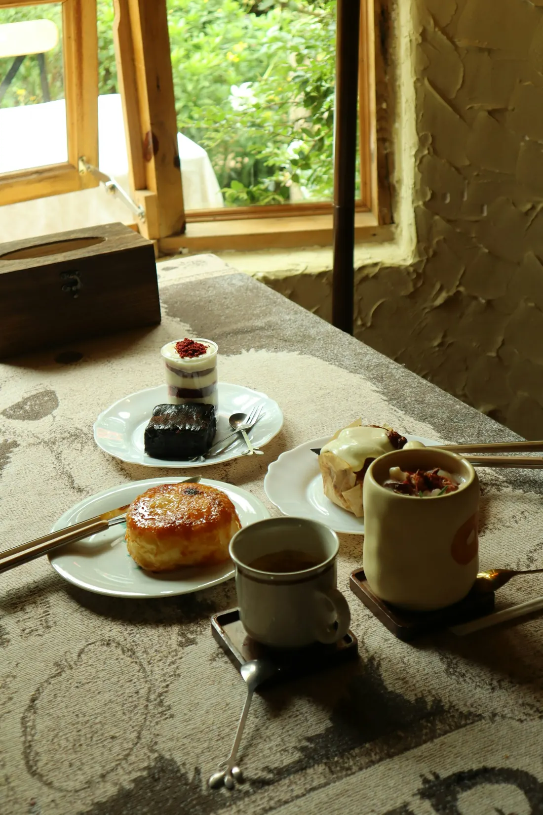 Té y postres servidos sobre una mesa junto a una ventana con luz de tarde