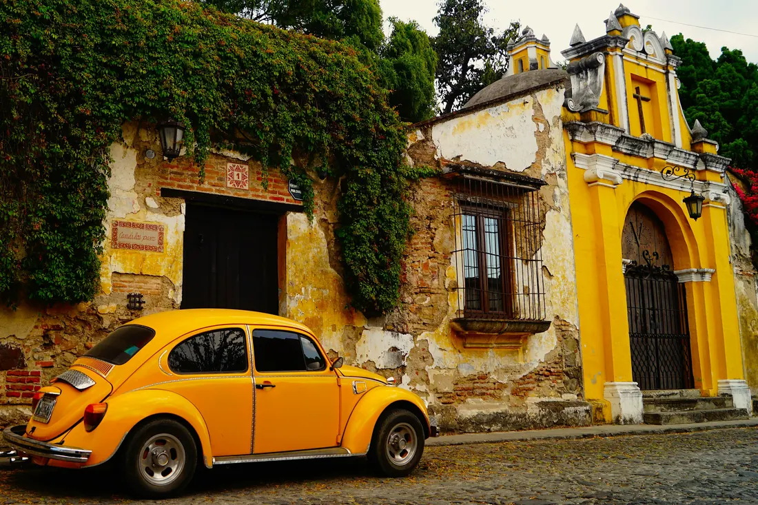 Escarabajo amarillo frente a una fachada colonial con enredaderas en Antigua Guatemala